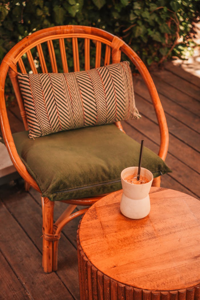 creative Bamboo chair with cushion and refreshing drink on a wooden patio, relaxing outdoor setting.